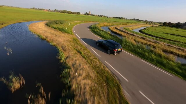 Following a passenger car transportation drive driving through the countryside fpv aerial drone view.