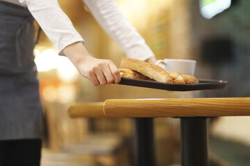 Waitress serving coffee and bread in cafe