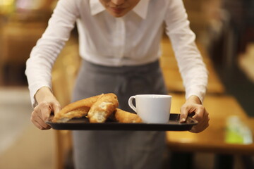 Waitress serving coffee and bread in cafe