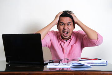 Adult Asian man showing stressed expression in his working table