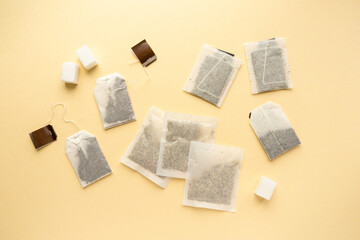 Flat lay of various tea bags on beige background, top view