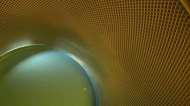 Moving down a metal grid where the base is blue, grid is gold. Wide angle view of the lines and patterns in the metal. RACK FOCUSING near end, DEFOCUSED for a couple seconds, then refocused at the end