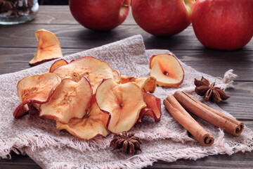 Heap of apple chips and cinnamon and red apples on background. Soft focus.