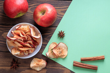 Top view of apple chips and cinnamon and red apples on a wooden table. With copy space.