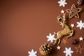 Christmas composition with golden deer, stars, pine cones, white snowflakes, brown background. Christmas deer background