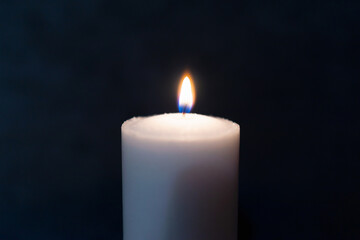 One single light candle burning brightly in the black background.Spiritual candle yellow flame. Flame of candle in the darkness.Copy space.