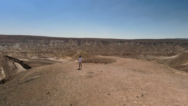 Aerial view footage of a man Hiking to Mountain Peak Revealing Beautiful Negev Desert Landscape. High quality 4k footage