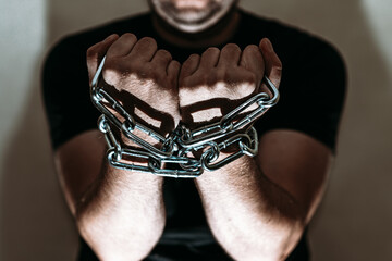Chained human hands sticking out in a prison.Gray wall.Selective focus.