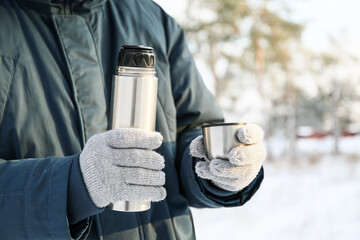 Young man with thermos on snowy day, closeup