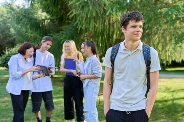 Portrait of male student in park campus, group of teenagers with teacher background