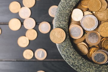 Bowl with golden coins on dark wooden background
