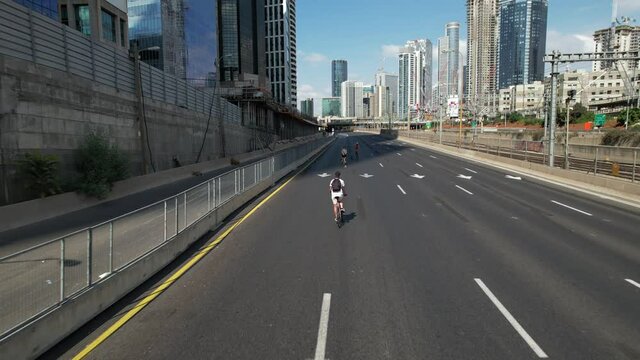 Aerial drone view following a person cycling on a empty highway in Tel Aviv, Israel, during Yom Kippur