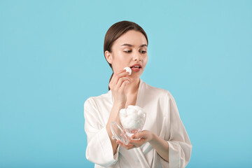 Beautiful young woman with cotton wool on color background