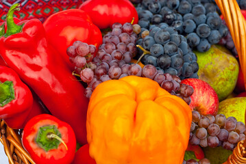 Apples, pears, grapes and peppers in a basket. Vegetables close up. Picnic food.