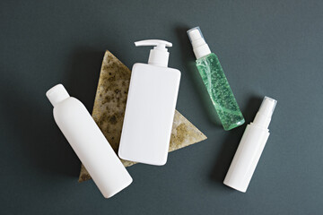 Set of white cosmetic bottles on dark green background.
