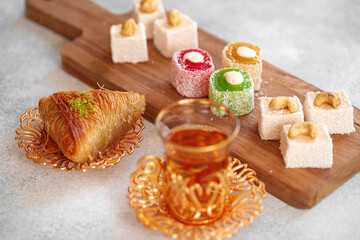 Various Turkish sweets and cup of tea on white textured background
