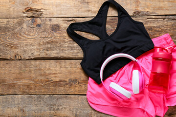 Sportswear, headphones and bottle for water on wooden background
