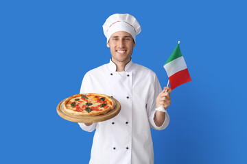 Handsome chef with delicious pizza and flag of Italy on blue background