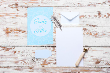 Cards with text EMILY & ALEX, envelope and stamp on white wooden background