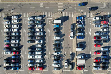 Top down view of many cars on a parking lot of a shopping center