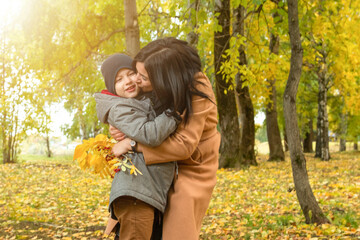 A mother kisses her son for giving her a bouquet.