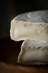 Homemade cheese with white mold on a dark wooden background