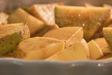 Sliced potatoes are baked on a platter in a home kitchen oven, close-up