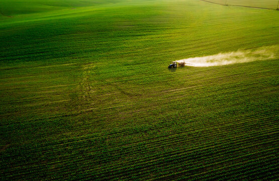 Scenic top view of a tractor spraying green fields.