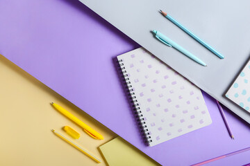 Notebooks, pens and pencils on color background, closeup