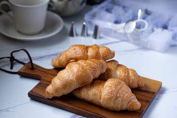 croissant on a brown plate next to a mug of milk on marble background