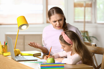 Little girl with her mother doing lessons at home