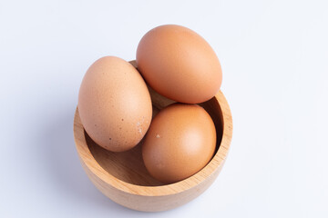 Three fresh eggs in a cup on a white background.