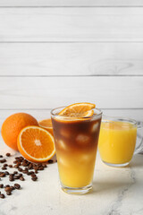Glass of tasty coffee with orange juice on table