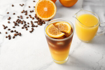 Glass of tasty coffee with orange juice on light background