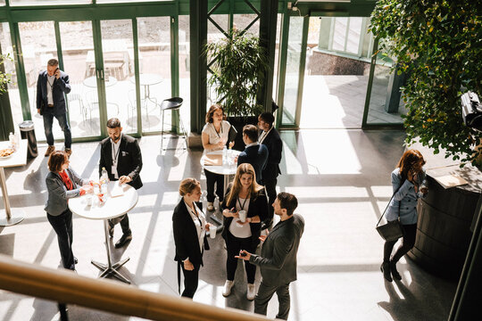 High angle view of businessmen and businesswomen discussing while standing together during networking at convention cent