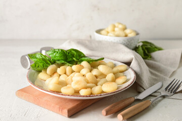 Plate with tasty gnocchi on light background
