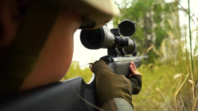 military take aim from a sniper rifle while sitting in ambush
