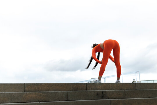 Young woman tired after running. Female athlete bending over catching her breath jogging.