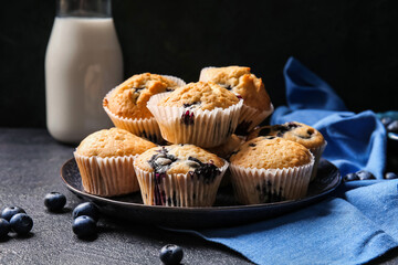 Plate with tasty blueberry muffins on dark background