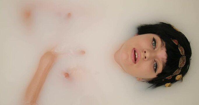 Attractive seductive girl. beautiful young woman with expressive eyes and seductive lips takes a bath of milk. Cleopatra