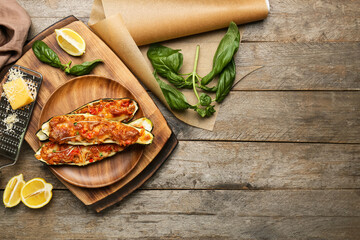 Plate with meat stuffed zucchini boats and ingredients on wooden background