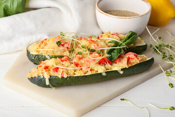 Board with quinoa stuffed zucchini boats on light background