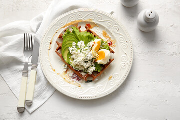 Delicious Belgian waffle with egg, cheese and avocado on light background