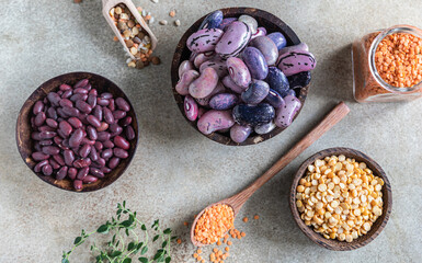 Assortment of beans and lentils on concrete background. The concept of healthy and nutritious food. Vegan high protein product. Top view.