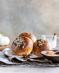 Fresh homemade pumpkin buns with brown sugar or seeds, light concrete background. Autumn bakery.