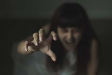 Female ghost in white dress in room. A young scary girl in an old white dress staring in to the camera ferociously with dark background. Asian woman make up ghost face at house. Scary horror concept.