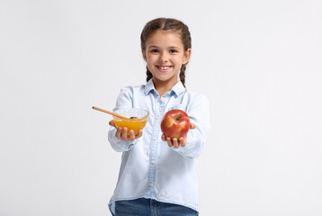 Little girl with honey and apple on white background. Rosh Hashanah (Jewish New Year) celebration