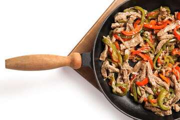 Frying pan with traditional Mexican Fajita and vegetables on white background