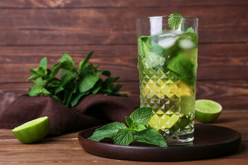 Glass of tasty mint tea with lemon and lime on dark wooden background