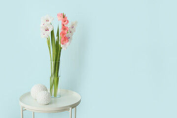 Vase with gladiolus flowers and decor on table in room
